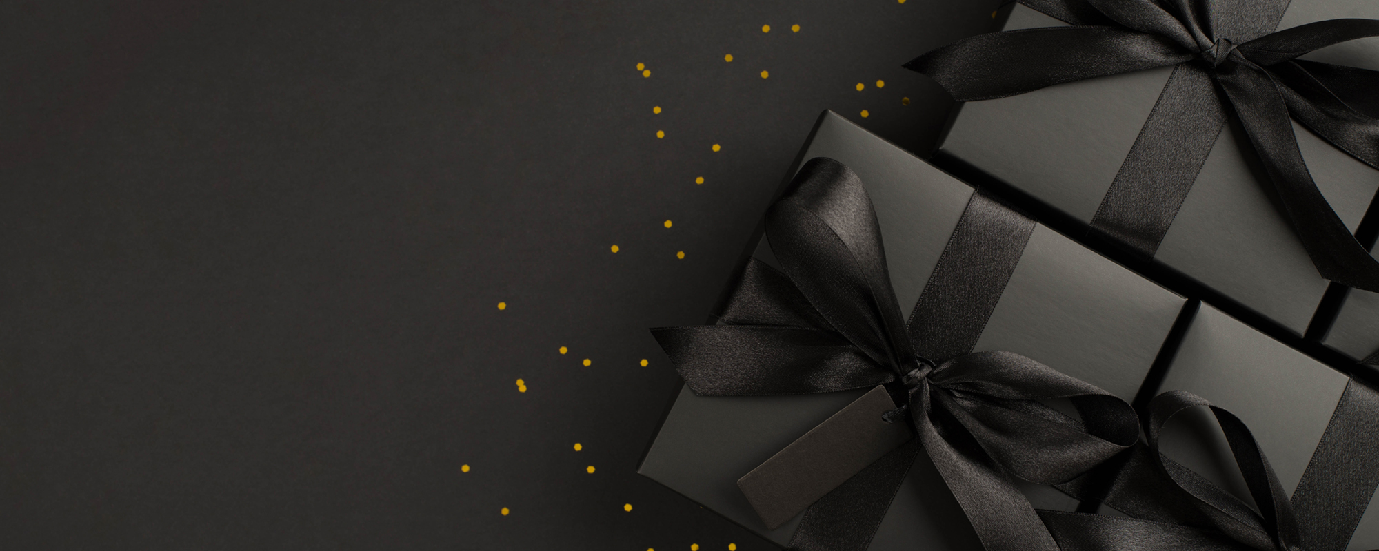 Gift boxes wrapped with black paper and ribbons and sprinkles of gold glitter